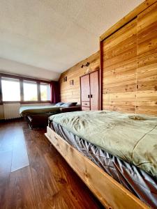 a bedroom with two beds and a wooden wall at Ski&Sky Studiò 85 in Pila +3 photos