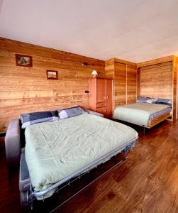 two beds in a room with wooden walls at Ski&Sky Studiò 85 in Pila