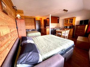 a bedroom with a large bed and a kitchen at Ski&Sky Studiò 85 in Pila