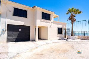 a white house with a garage and a palm tree at InTown Beach front condo - Casey`s condo 1 in San Felipe