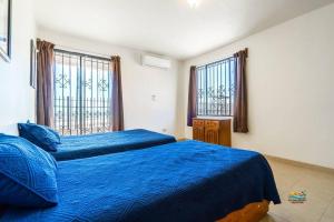 a bedroom with two beds with blue sheets and windows at InTown Beach front condo - Casey`s condo 1 in San Felipe