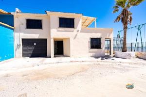 a white house with a palm tree in front of it at InTown Beach front condo - Casey`s condo 1 in San Felipe