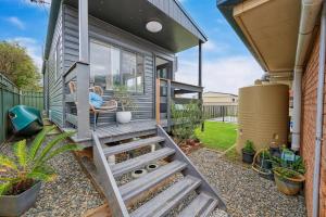 a person sitting in a chair on the porch of a tiny house at The Drift at Cathie in Lake Cathie