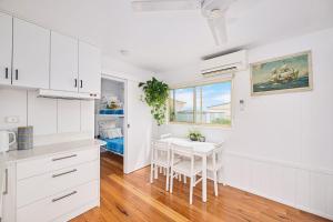 a kitchen with white cabinets and a white table at The Drift at Cathie in Lake Cathie