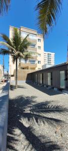 a building with two palm trees in front of it at Refúgio ensolarado a poucos passos do mar in Navegantes
