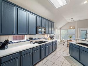 a large kitchen with blue cabinets and a sink at Boho Dreamscape 4BD Game Room Pool in The Colony