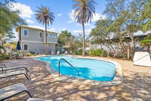 a swimming pool with palm trees and a house at Soakin it Up in Inlet Beach