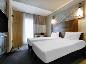 a hotel room with two beds and a television at Ibis Aktobe in Aktobe