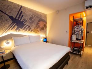 Un dormitorio con una gran cama blanca con un cuadro en la pared. en ibis Styles Lima Benavides Miraflores, en Lima