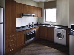 a kitchen with a sink and a washing machine at Mövenpick Hotel & Apartments Bur Dubai in Dubai