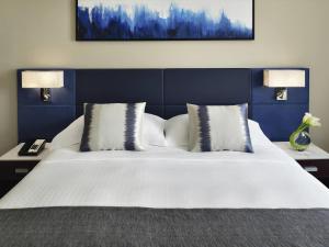 a bedroom with a large white bed with two lamps at Mövenpick Hotel & Apartments Bur Dubai in Dubai