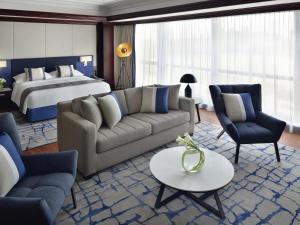 a living room with a bed and a couch and chairs at Mövenpick Hotel & Apartments Bur Dubai in Dubai