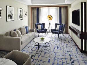 a living room with a couch and chairs and a tv at Mövenpick Hotel & Apartments Bur Dubai in Dubai +151 photos