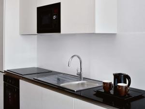 Una cocina con un fregadero y dos tazas en una encimera. en Mövenpick Hotel Apartments Downtown Dubai, en Dubái