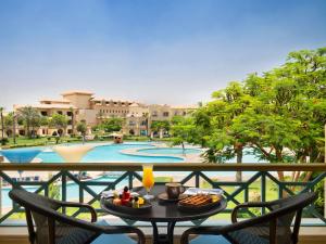十月六日城Mövenpick Hotel Cairo - Media City的池景阳台的餐桌