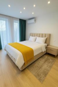 a bedroom with a large bed with a yellow blanket at Roots One - Lakeview Escape with Balcony & Parking in Bucharest +57 photos