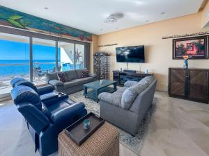 a living room with couches and a flat screen tv at Waves & Relaxation Oceanfront 2BR Family Condo in Puerto Peñasco +60 photos