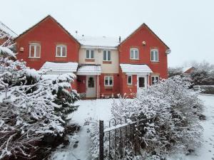 ein rotes Haus mit Schnee auf dem Boden in der Unterkunft Themed Cosy Home by Cannock Chase Forest in Rugeley