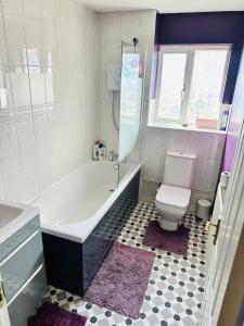 a bathroom with a white tub and a toilet at Themed Cosy Home by Cannock Chase Forest in Rugeley