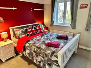 a bedroom with a bed with a red wall at Themed Cosy Home by Cannock Chase Forest in Rugeley
