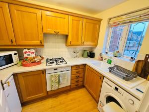 a kitchen with wooden cabinets and a stove top oven at Themed Cosy Home by Cannock Chase Forest in Rugeley +21 photos