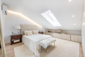 a white bedroom with a bed and a skylight at Riverside duplex by the sea with pool and balcony in Fão