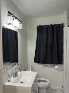 a bathroom with a sink and a black shower curtain at Oilgate at Parkgate in Akron +21 photos