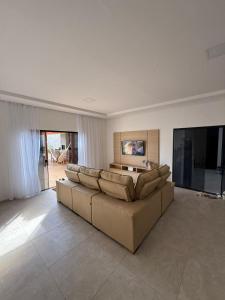 a living room with a large couch and a television at Pousada Essencia de Pipa in Pipa