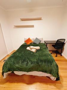 une chambre avec un lit vert avec une chaise dans l'établissement Modern 2 bedroom home in burwood east, à Burwood East