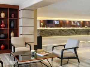 a hotel lobby with two chairs and a table and a table at Anwar Al Madinah Mövenpick in Al Madinah