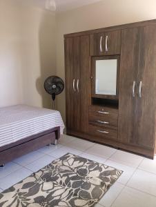 a bedroom with a large wooden cabinet and a rug at Casa de Verão, 04 quartos todos com ar condicionado, 03 banheiros, churrasqueira e piscina para relaxar in Pirapora