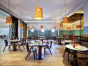 a dining room with tables and chairs and lights at ibis Styles Bandung Grand Central in Bandung