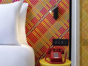 a red phone sitting on a table next to a bed at ibis Styles Bangkok Silom in Bangkok