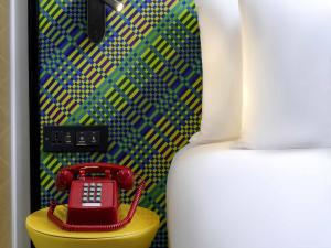 a red phone sitting on a yellow table next to a bed at ibis Styles Bangkok Silom in Bangkok