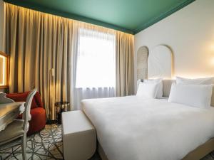 ソポトにあるRezydent Hotel Sopot - MGallery Collectionの大きな白いベッドと窓のあるホテルの部屋