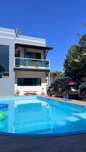 a house with a swimming pool in front of a house at Casa de Verão, 04 quartos, 03 banheiros, piscina e churrasqueira para relaxar in Pirapora