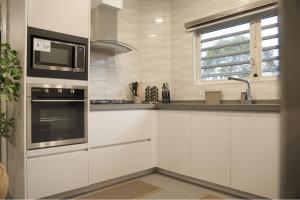 a white kitchen with a microwave and a stove at Cozy Stay in Paramaribo North in Paramaribo