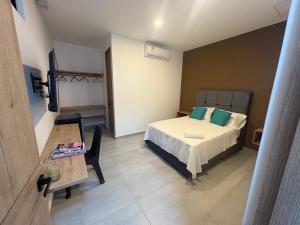 a small bedroom with a bed and a table at Hotel El Cedro Exclusive in Florencia