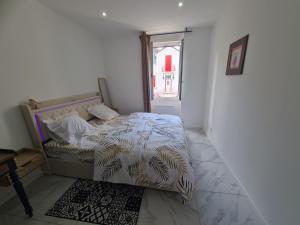 a bedroom with a bed with a comforter and a window at Rive gauche Rive droite 2 Appartements côte à côte neufs et bien équipés in Le Creusot