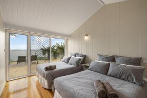 two beds in a bedroom with a view of the ocean at Waterfront Seabreeze Cowes in Cowes
