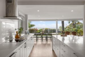 a kitchen with white cabinets and a table with chairs at Waterfront Seabreeze Cowes in Cowes