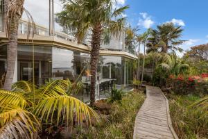 a wooden walkway leading to a house with palm trees at Waterfront Seabreeze Cowes in Cowes