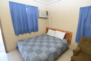 a bedroom with a bed and a chair and blue curtains at San Felipe Rental Studio #1 Free WiFi and Cable TV in San Felipe