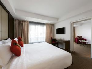 a hotel room with a large bed and a desk at Movenpick Suriwongse Hotel Chiang Mai in Chiang Mai