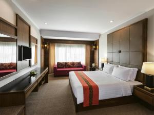 a hotel room with a bed and a couch at Movenpick Suriwongse Hotel Chiang Mai in Chiang Mai