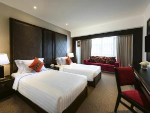 a hotel room with two beds and a red couch at Movenpick Suriwongse Hotel Chiang Mai in Chiang Mai