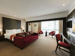 a hotel room with a bed and a red couch at Movenpick Suriwongse Hotel Chiang Mai in Chiang Mai +56 photos