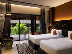 a hotel room with two beds and a balcony at Grand Mercure Khao Lak Bangsak in Khao Lak