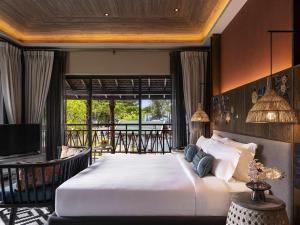a bedroom with a large bed and a balcony at Grand Mercure Khao Lak Bangsak in Khao Lak