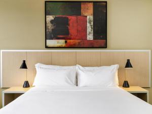 a bedroom with a white bed and two lamps at Mercure Rockhampton in Rockhampton
